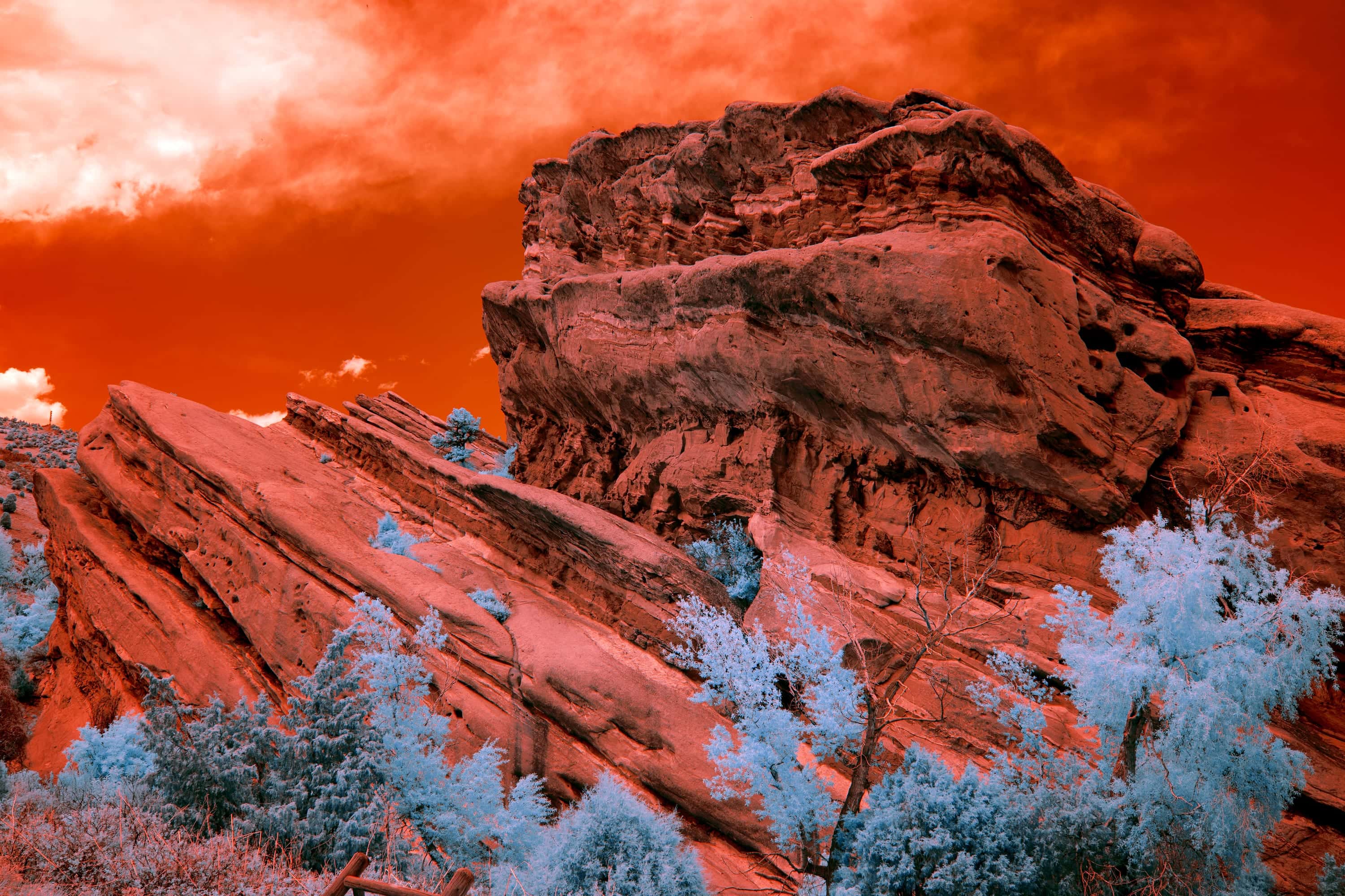 Upturned slabs of red sandstone leaning against a larger weathered outcrop in the foothills west of Denver, photographed in near-infrared light.