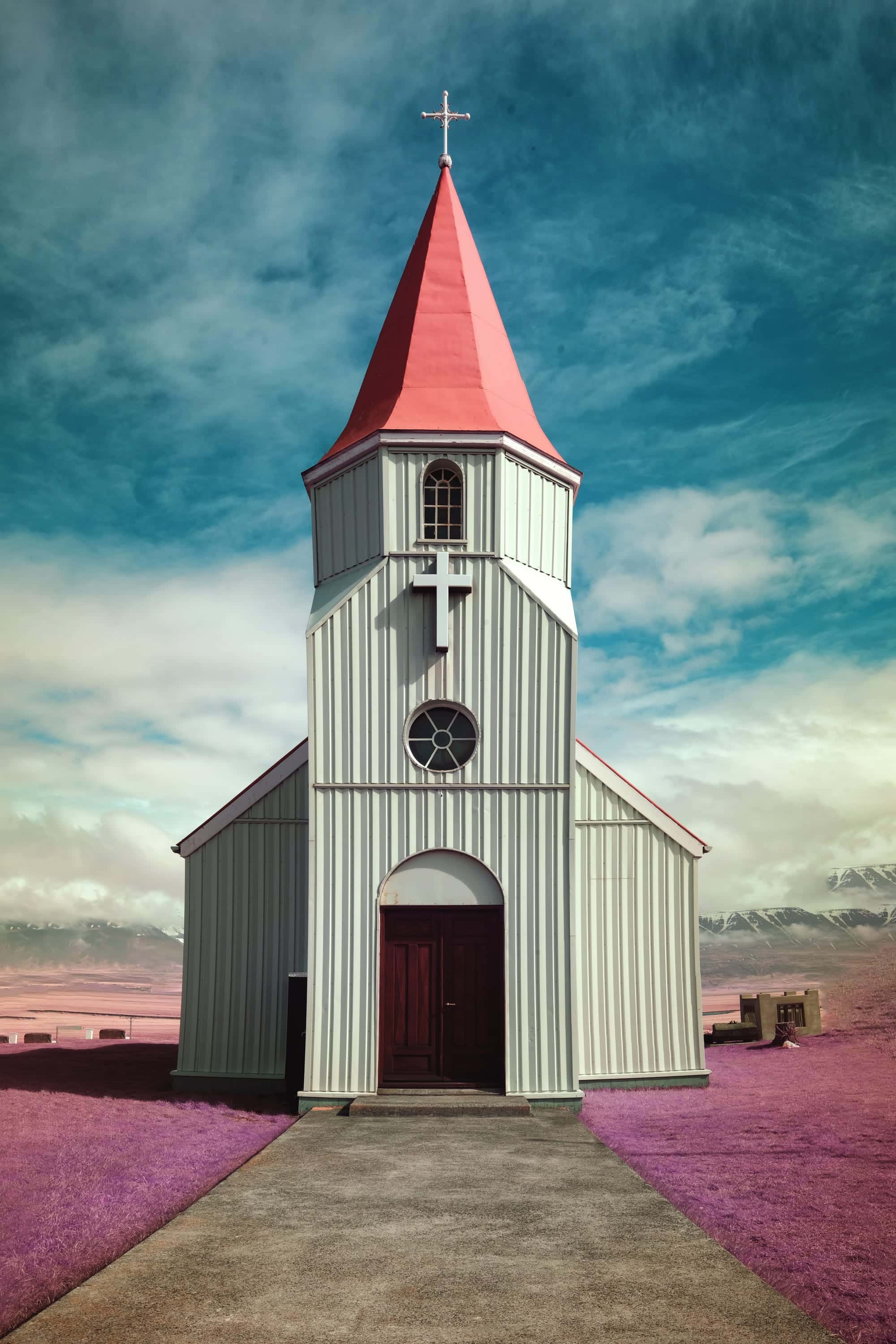A corrugated country church with a scarlet steeple, standing alone on violet ground under a teal sky